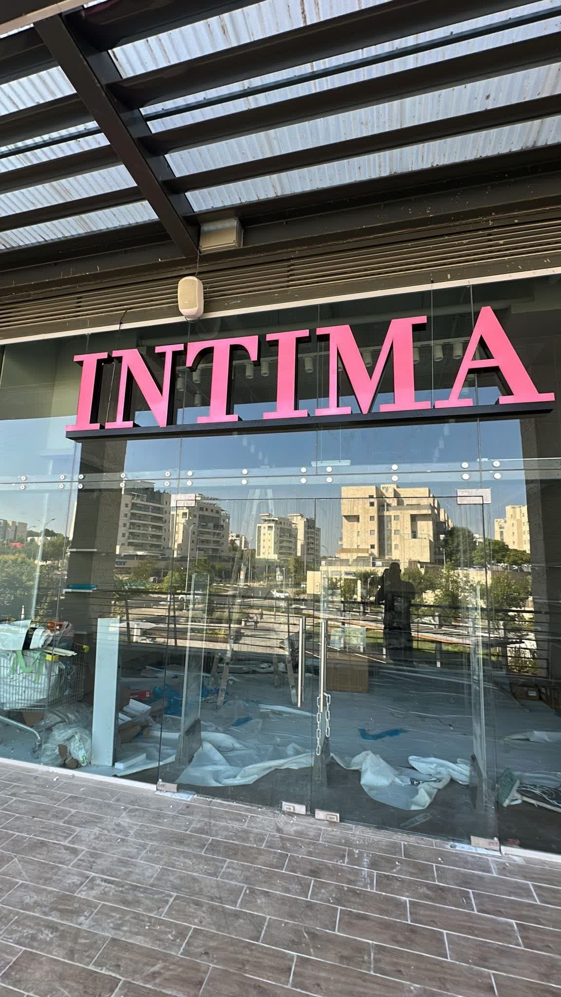 אותיות INTIMA ורודות מוארות על חזית זכוכית