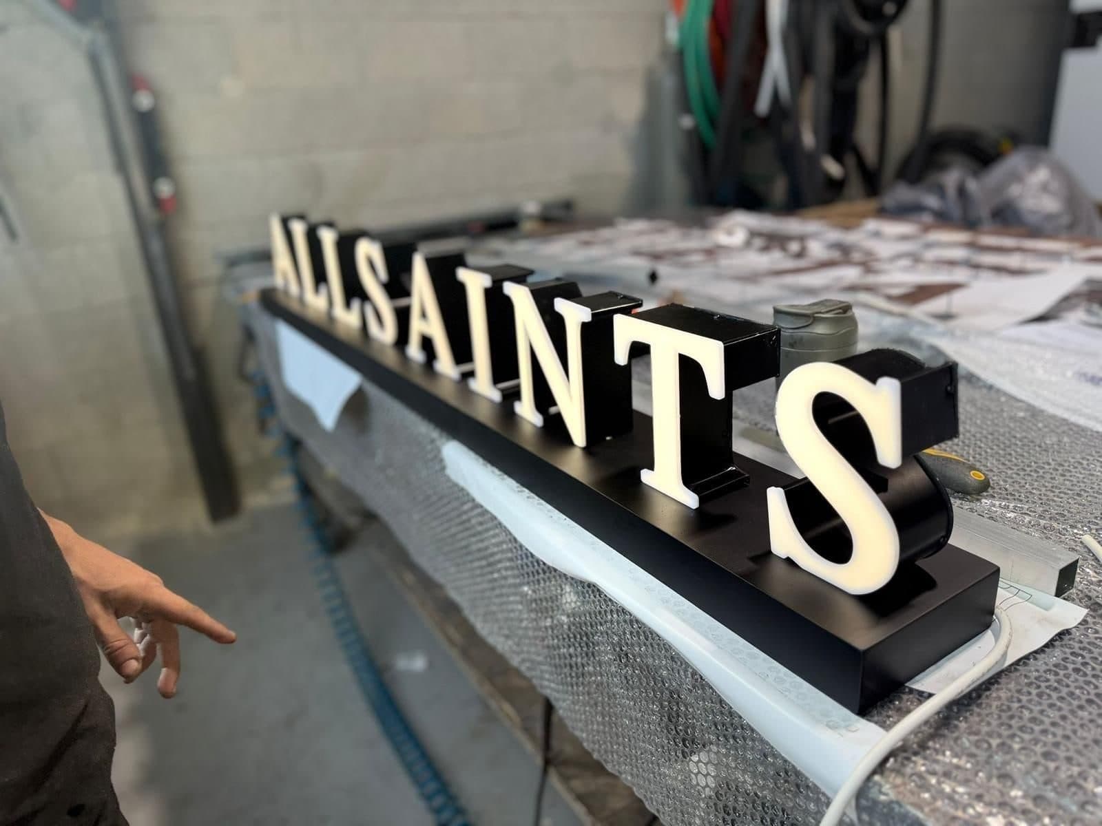 אותיות ALLSAINTS מוארות על שולחן העבודה במפעל