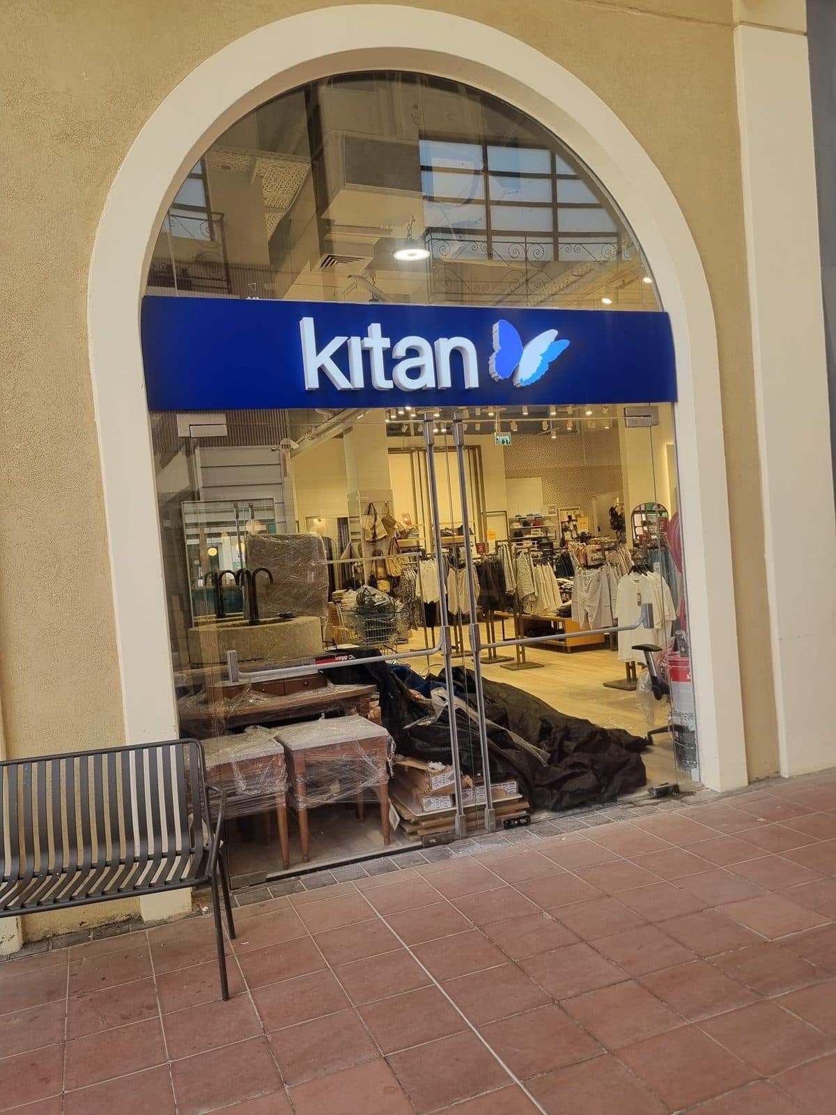 שלט kitan כחול עם אותיות לבנות ופרפר תלת-ממדי בכניסה מקושתת