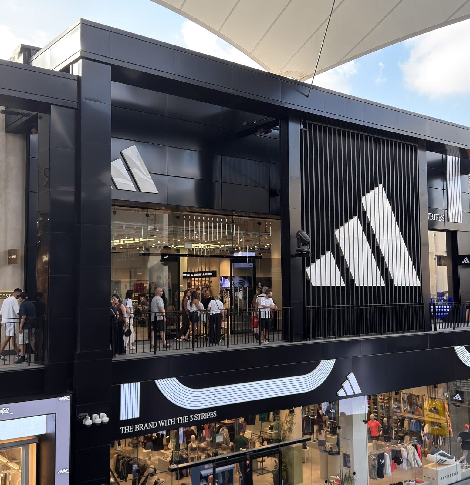 חזית adidas בביג גלילות — חיפוי שחור, לוגו המותג ופסי המותג על שתי הקומות