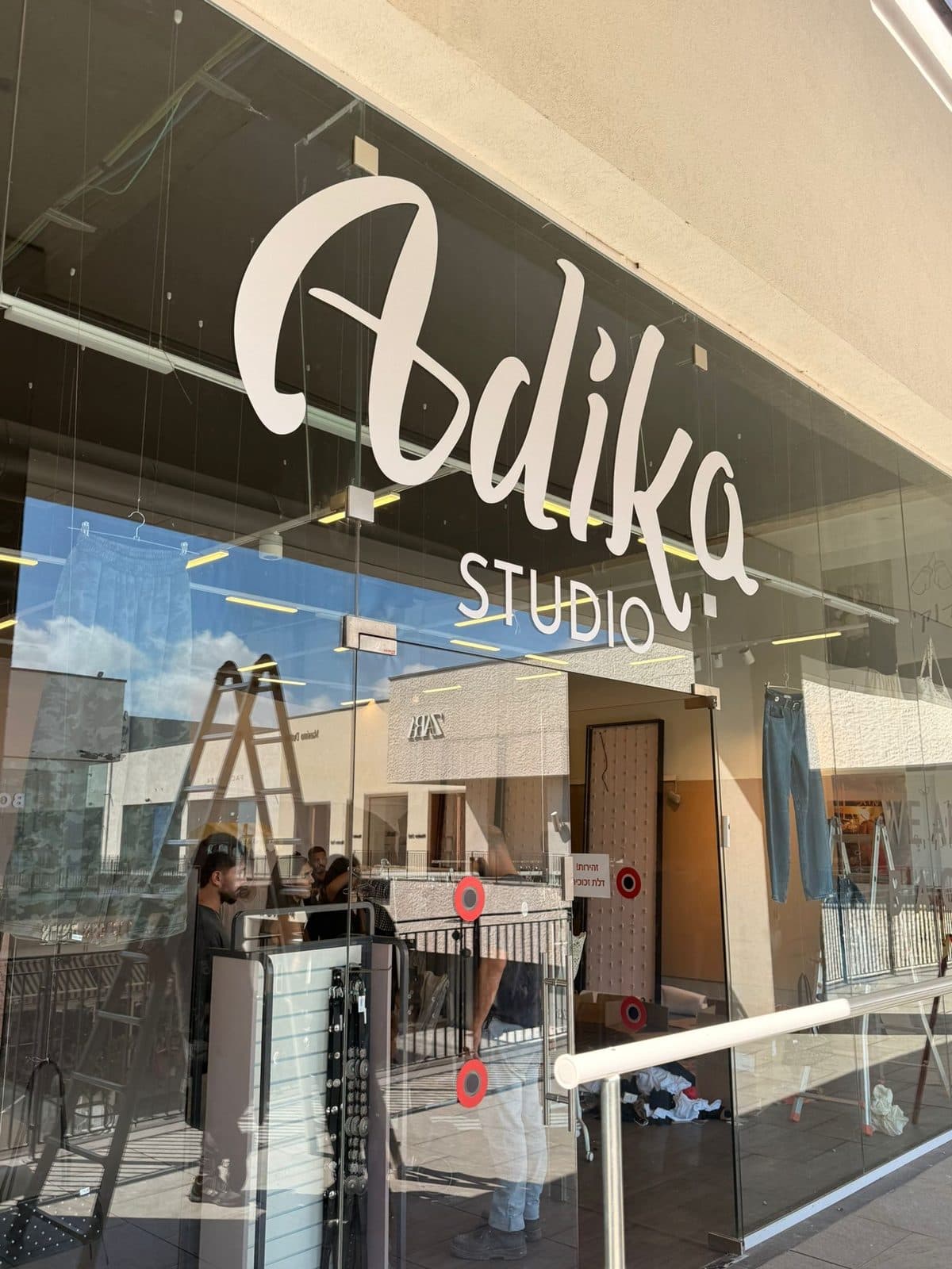 לוגו Adika Studio לבן על חזית זכוכית של החנות
