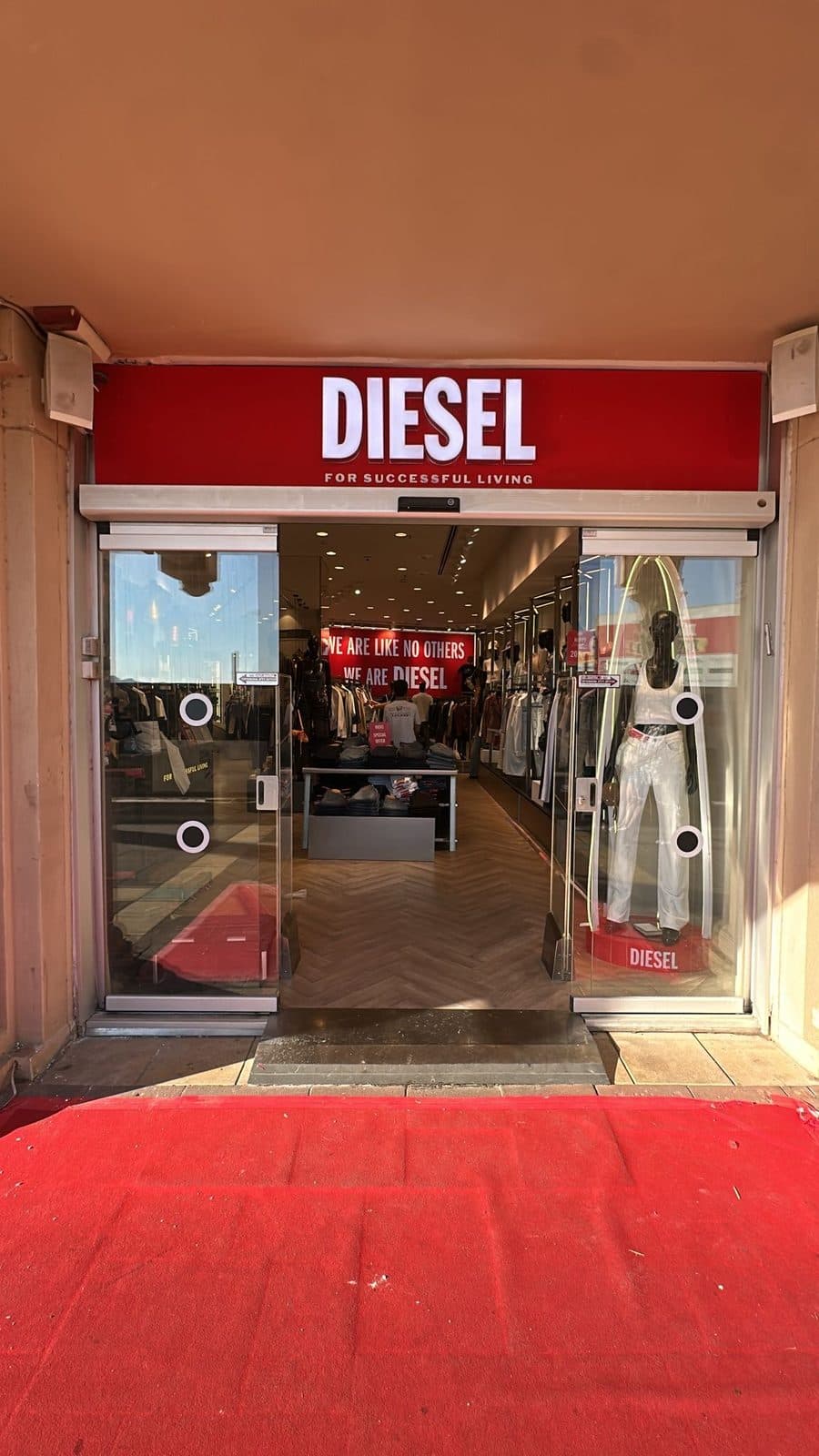 כניסה אדומה לחנות DIESEL עם שלט מואר ושטיח אדום