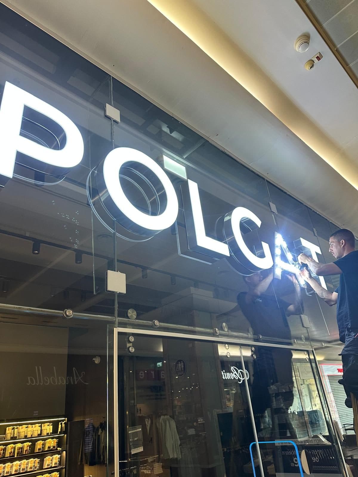 אותיות POLGAT מוארות על חזית זכוכית במהלך ההתקנה
