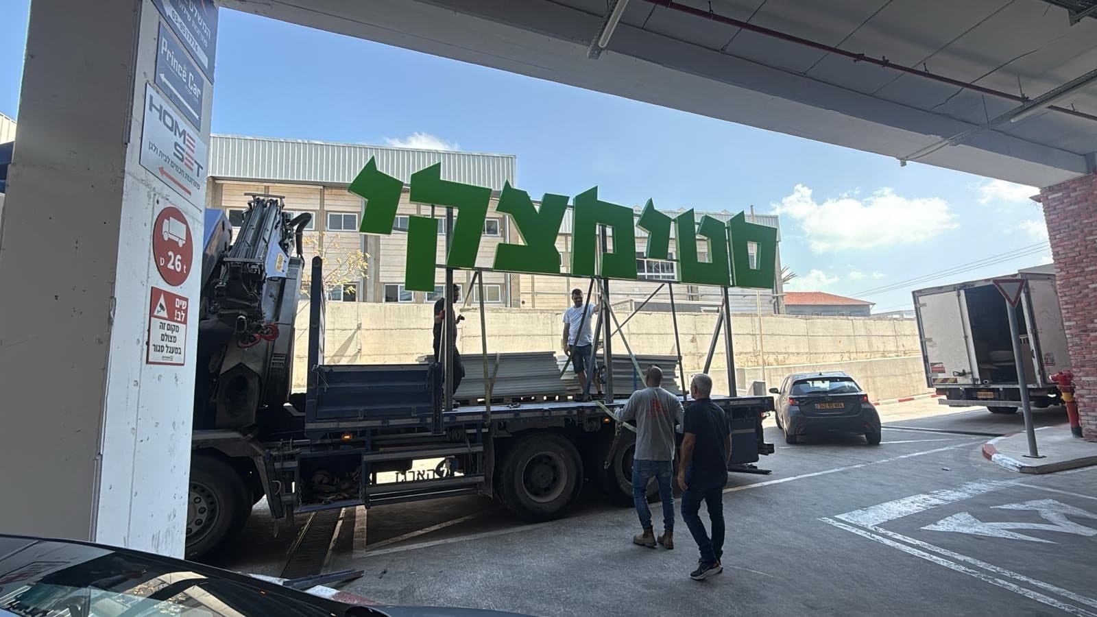 אותיות סטימצקי ירוקות על משאית מנוף בדרך להתקנה