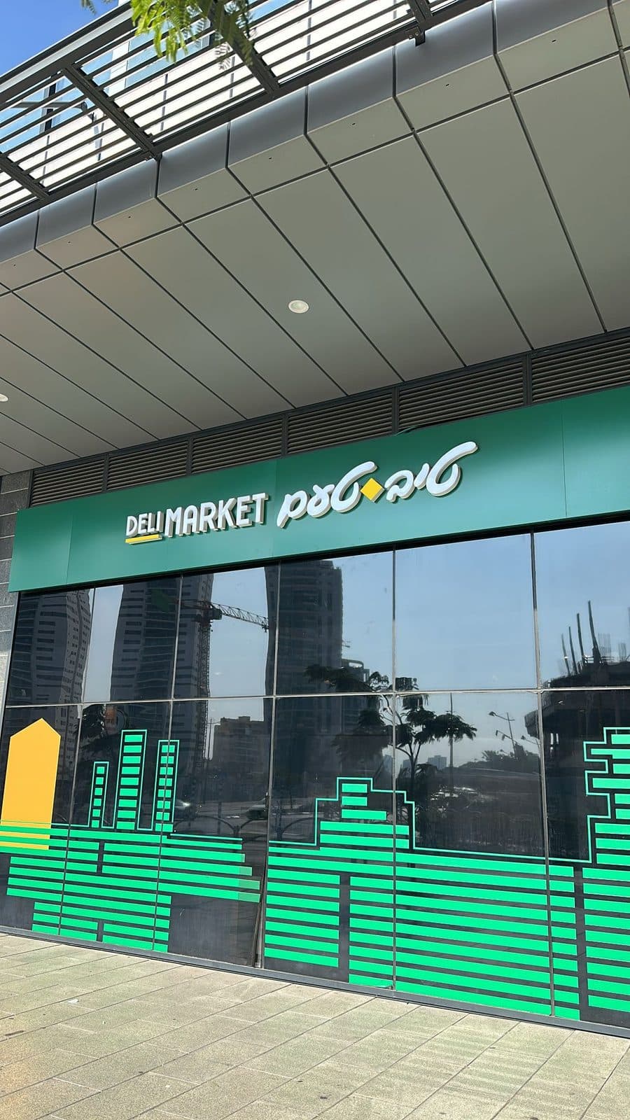 שלט חזית ירוק של טיב טעם DELI MARKET והדפסת קו רקיע על חלונות הזכוכית