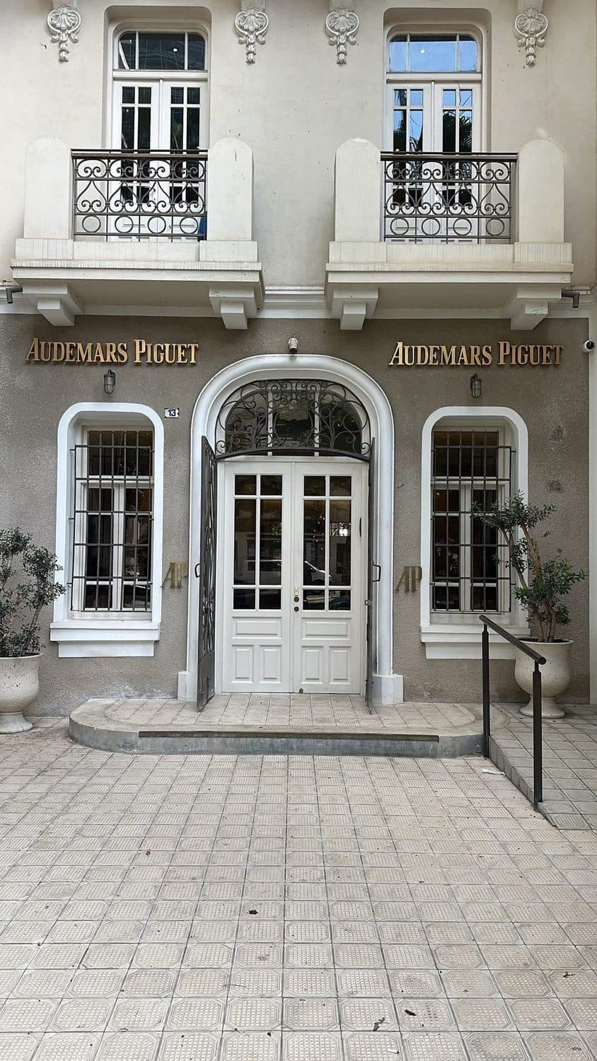 חזית AP House תל אביב — שני שלטי Audemars Piguet מפליז מוזהב משני צידי הכניסה המקושתת