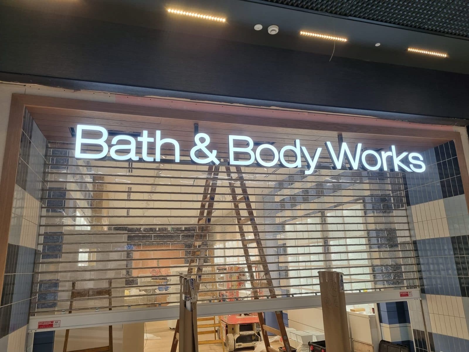 אותיות Bath & Body Works לבנות ומוארות על חיפוי העץ בחזית החנות