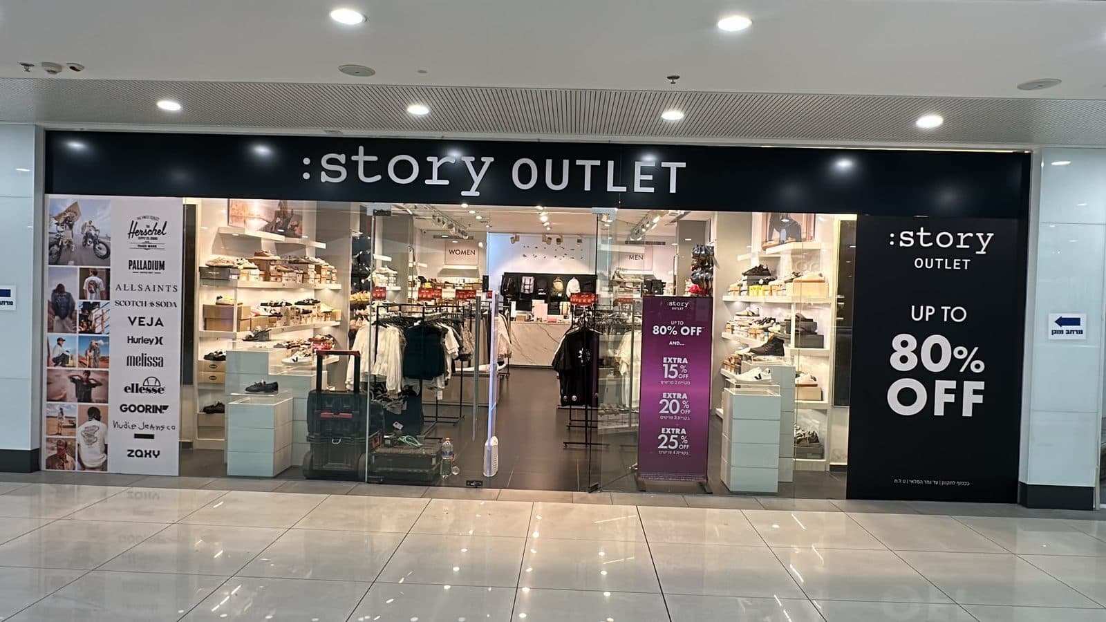 חזית :story OUTLET בקניון — שלט שחור עם אותיות לבנות ופאנלי מבצע משני הצדדים